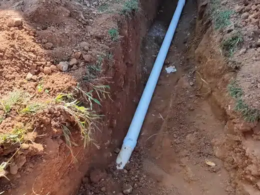 Open trench with sewer or water line replacement pipe exposed for Plumbing Services in Bellflower, CA
